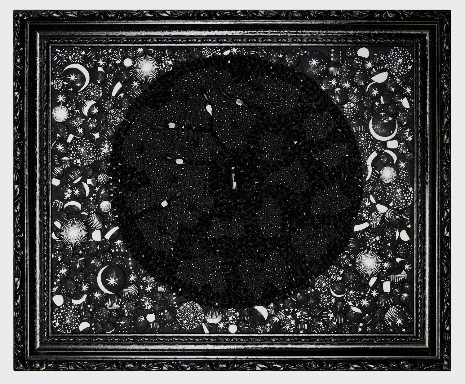 Planète noire texturée de perles en forme de pics entourée d’un ciel d’étoiles brodées, cadre noir