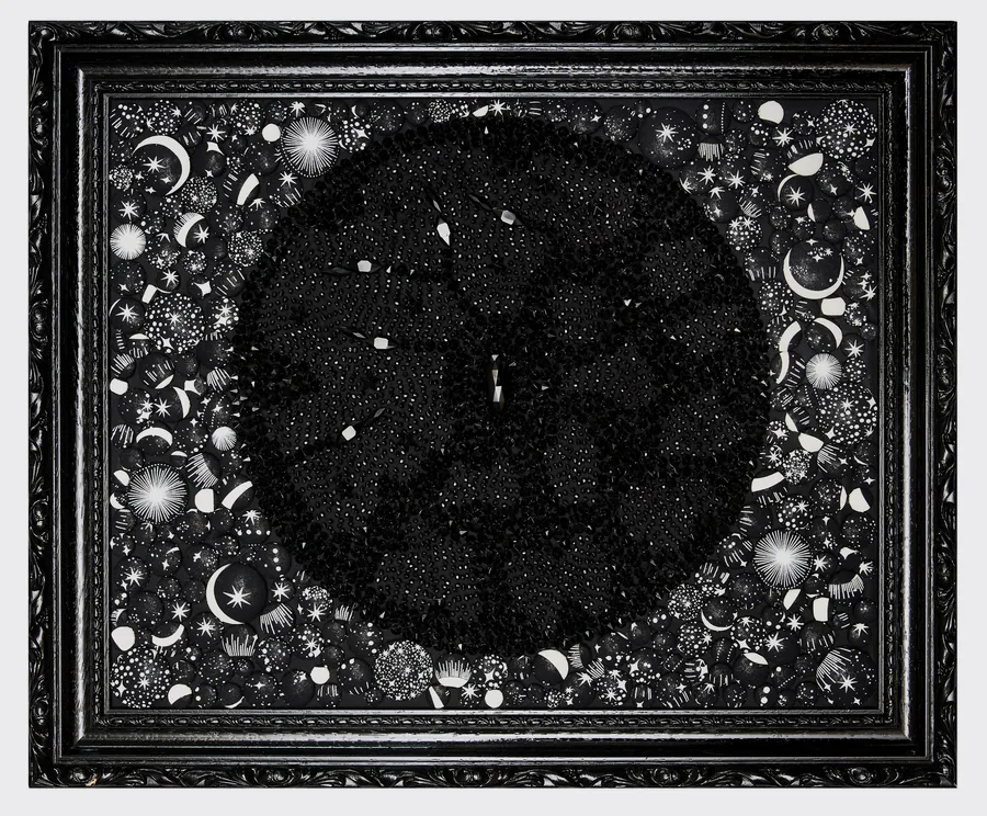 Planète noire texturée de perles en forme de pics entourée d’un ciel d’étoiles brodées, cadre noir
