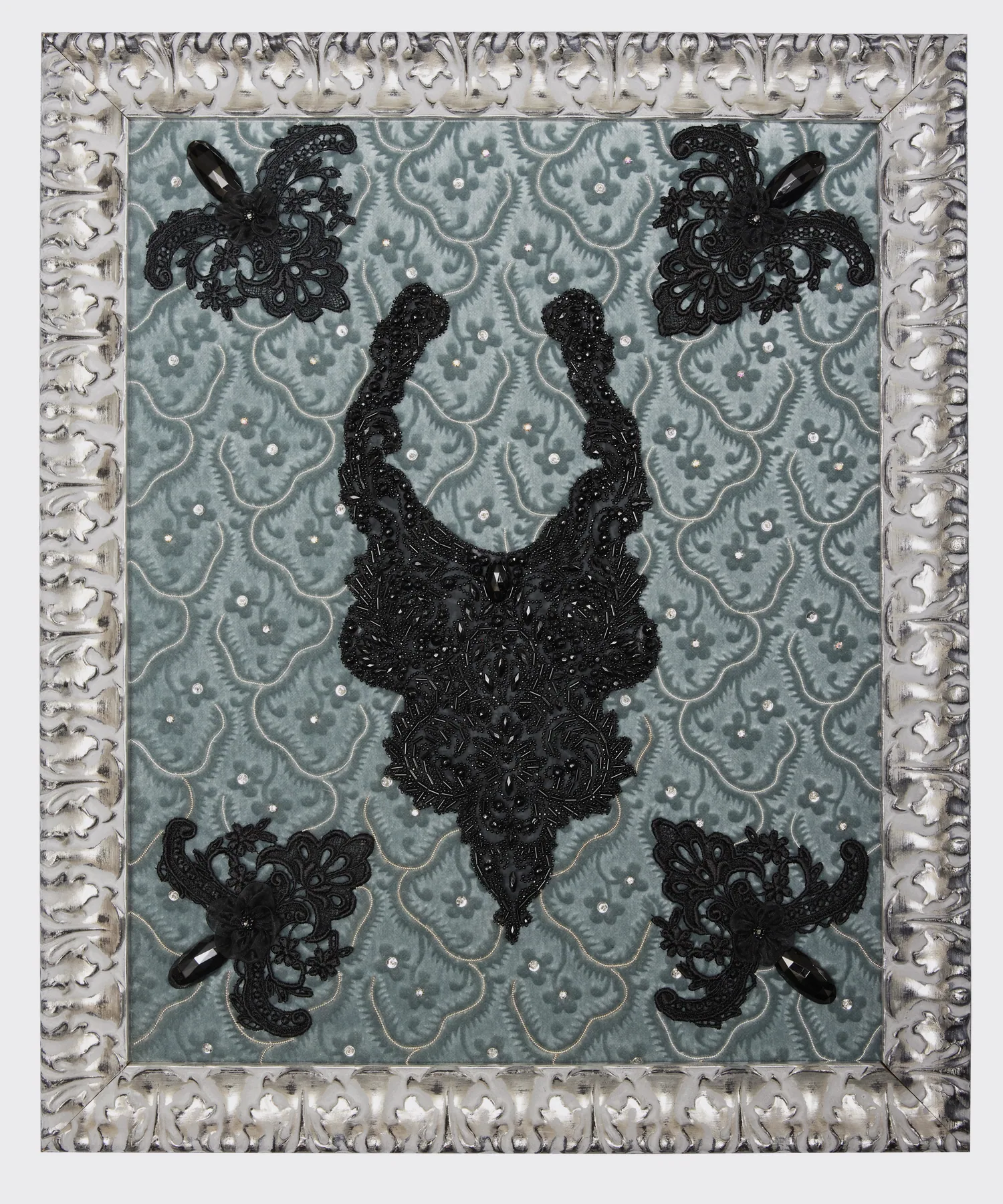 Collier brodé de perles et de cabochons noirs sur un fond gris-bleu, cadre argenté