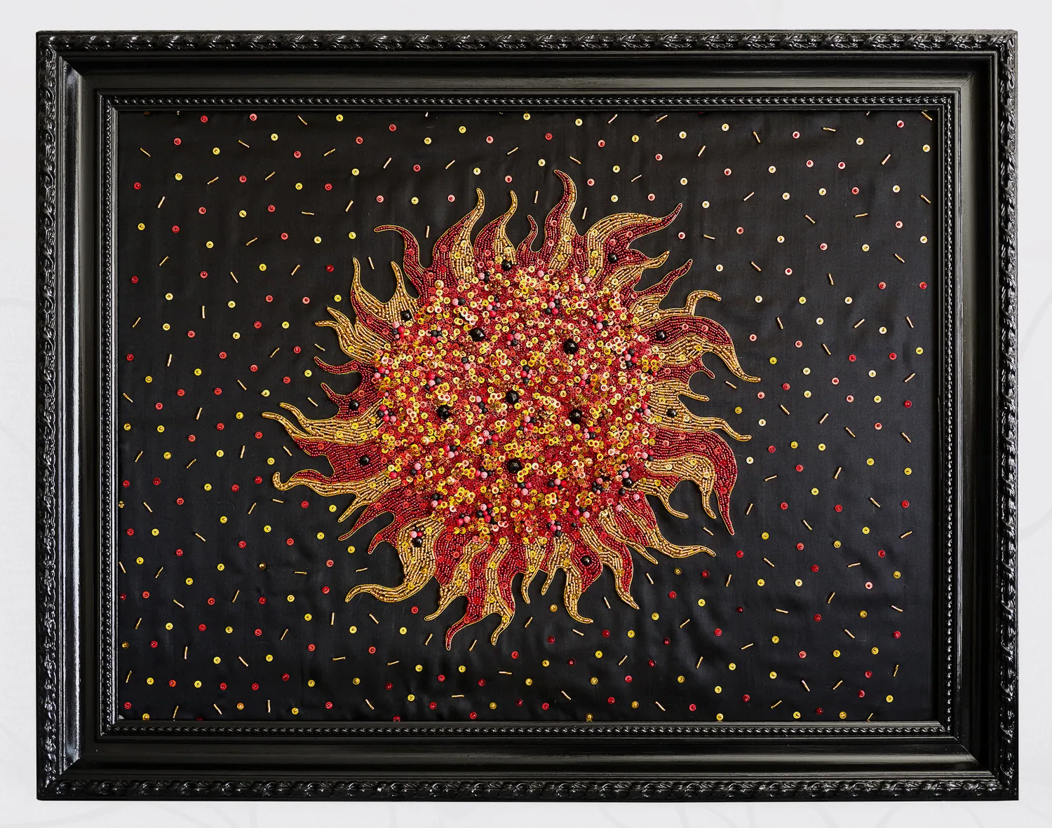 Soleil en éruption brodé de perles rouges et dorées sur soie noire, cadre noir sculpté