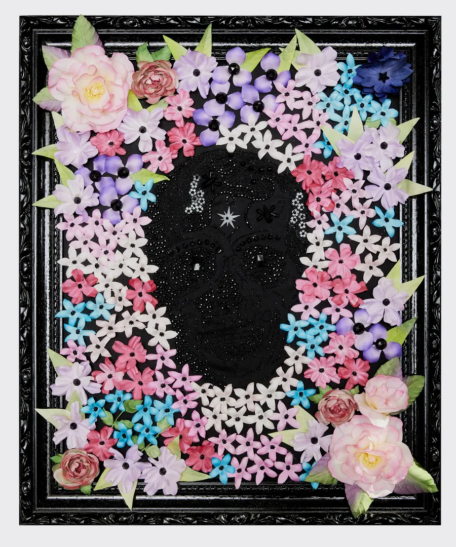Tête de mort brodée de perles noires entourée de fleurs en soie roses, violettes et bleues, cadre noir